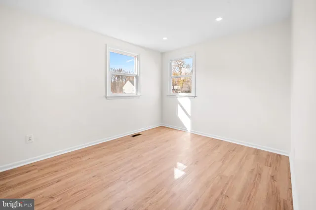 an empty room with wooden floor and window