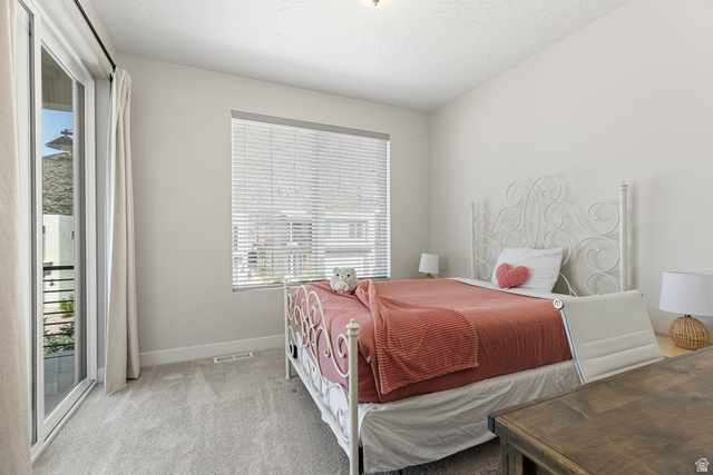 839 Walker Way St. George, UT 84770 - Photo 28 of 32 Bedroom featuring plush gray carpeting, a large window with blinds, and a glass-paneled door opening to an exterior area with a metal railing