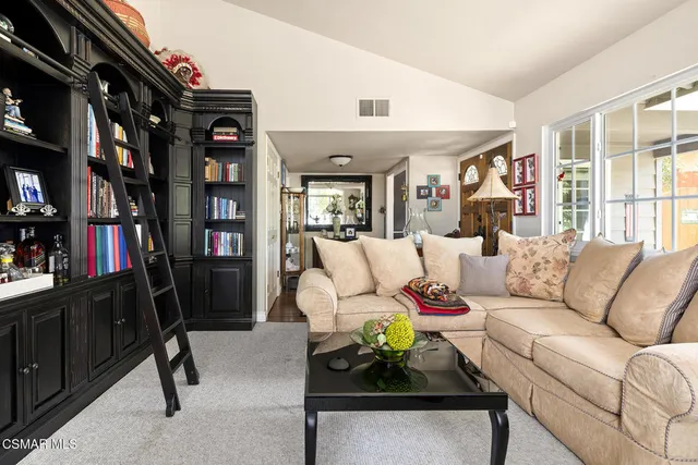 a living room with furniture a bookshelf and a window