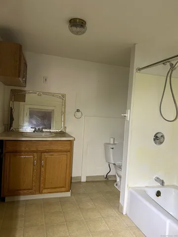 a bathroom with a granite countertop sink a toilet and shower
