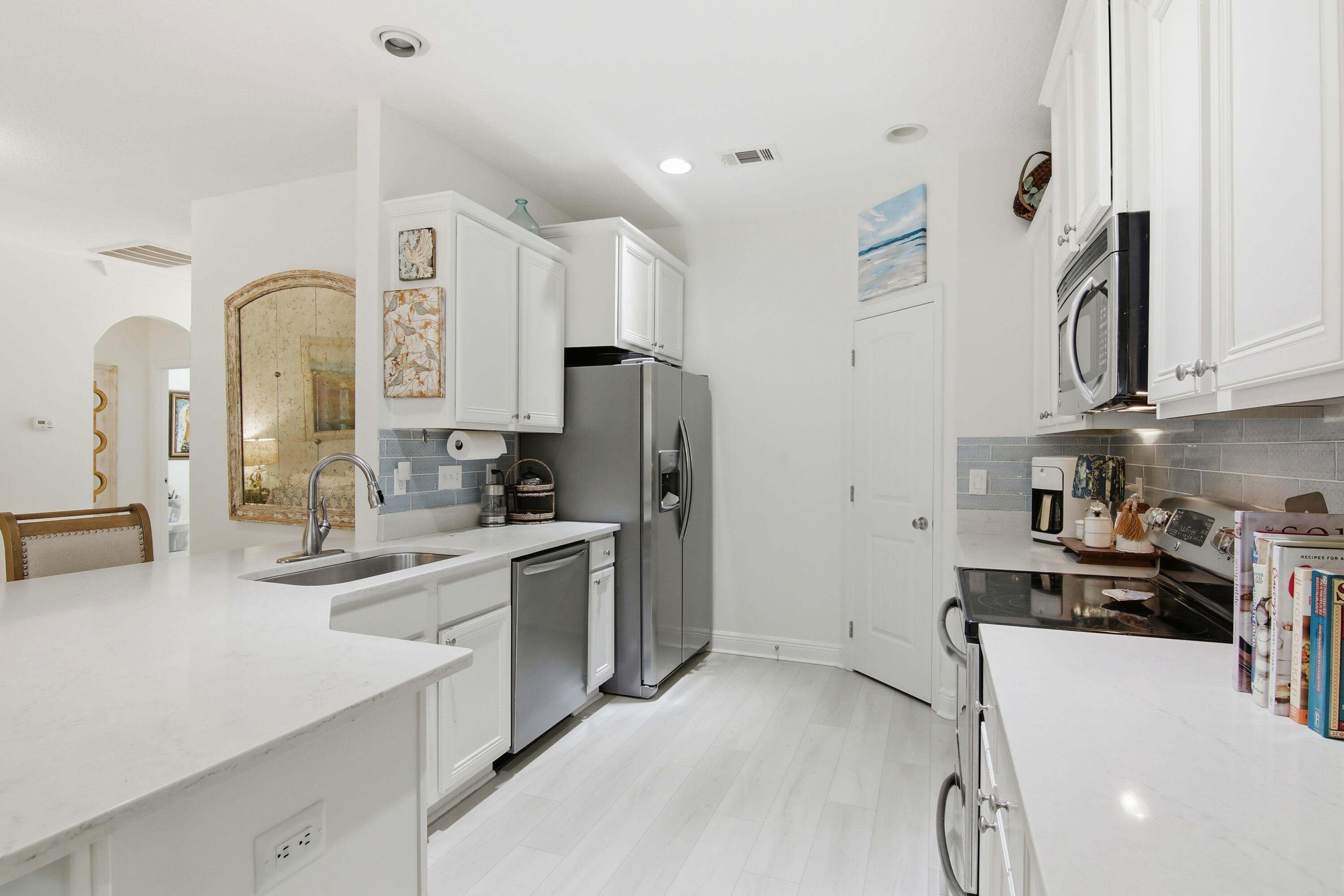 169 Marsh Landing North Freeport, FL 32439 - Photo 11 of 44 a kitchen with stainless steel appliances white cabinets a sink a stove a refrigerator and island with wooden floor
