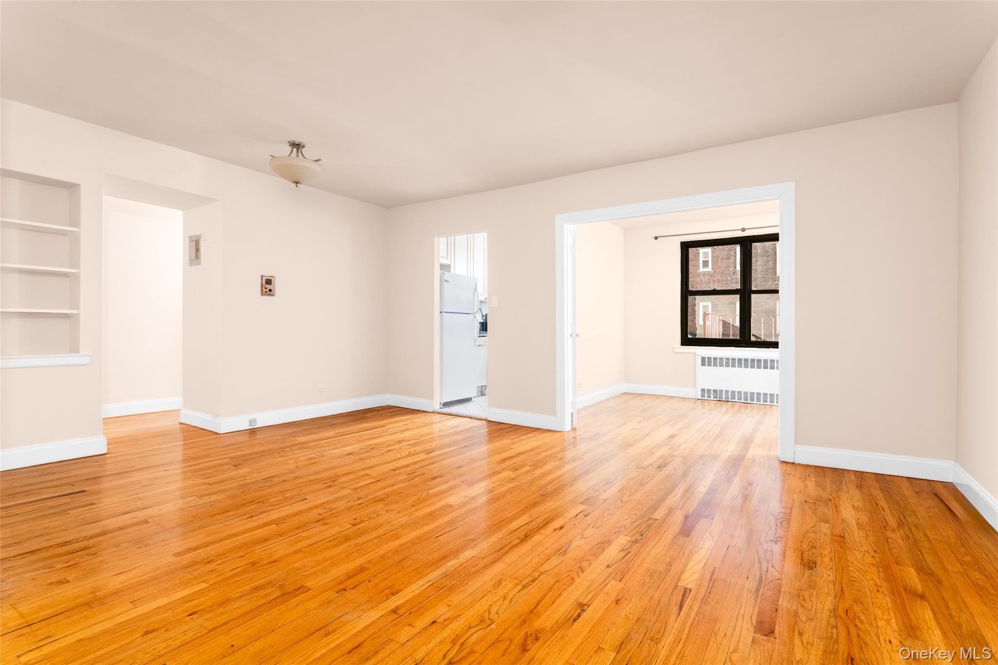 100-11 67th Road, Unit 205 Forest Hills, NY 11375 - Photo 3 of 15 an empty room with wooden floor and windows