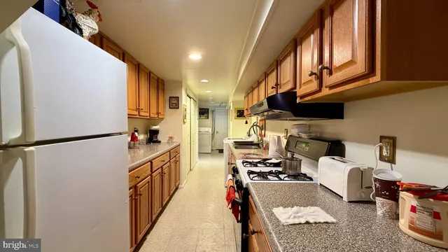 a kitchen with stainless steel appliances kitchen island granite countertop a refrigerator a stove and a sink with wooden floor