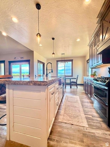 2101 Goose Ranch Road Vernal, UT 84078 - Photo 16 of 72 Kitchen featuring an expansive central island with a stone-finish countertop, white cabinetry, and pendant lighting