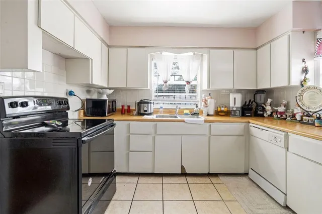 a kitchen with white cabinets appliances a sink and a window