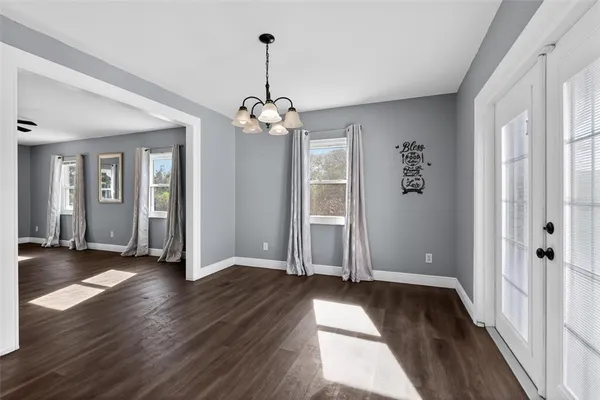 a view of an empty room with wooden floor and windows