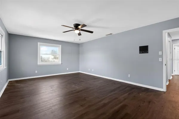 a view of an empty room with a window and wooden floor