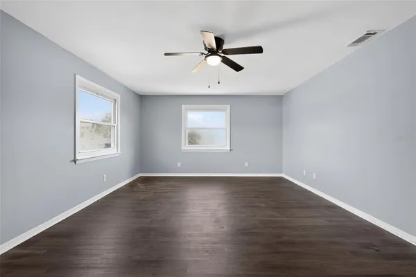 a view of empty room with wooden floor and fan