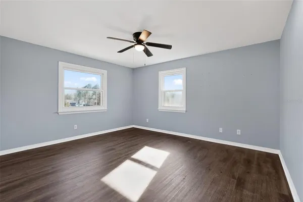 a view of empty room with wooden floor and fan