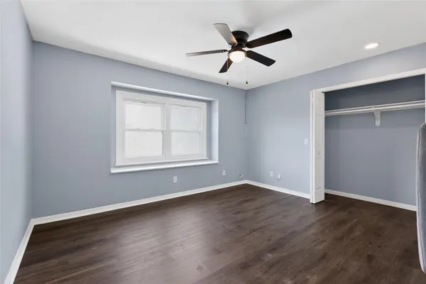 a view of an empty room with window and wooden floor