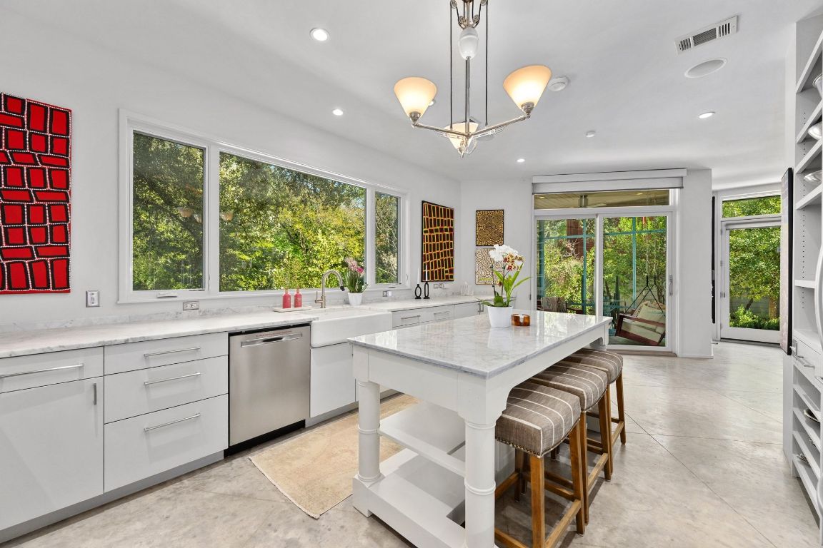 3705 Bridle Path Austin, TX 78703 - Photo 6 of 26 a kitchen with kitchen island granite countertop a stove a sink a large island with windows and chairs