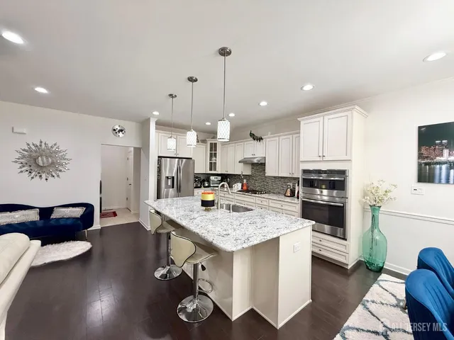 a kitchen with a sink a stove a refrigerator and white cabinets with wooden floor