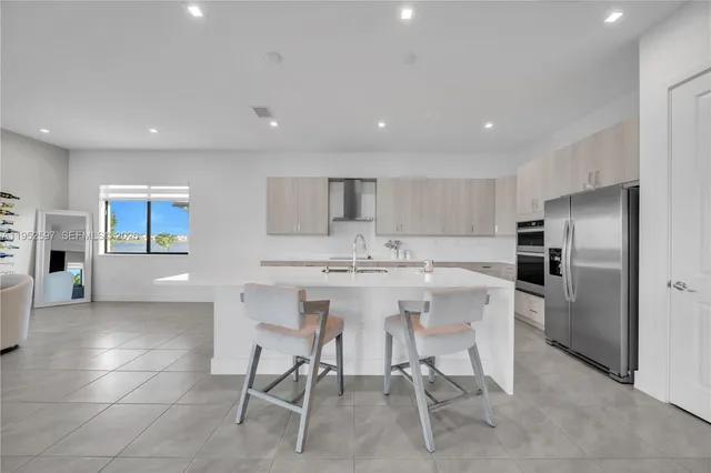 a kitchen with a sink chairs and refrigerator