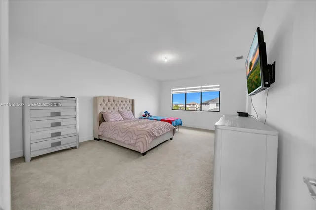 a bedroom with a bed a flat screen tv and dresser