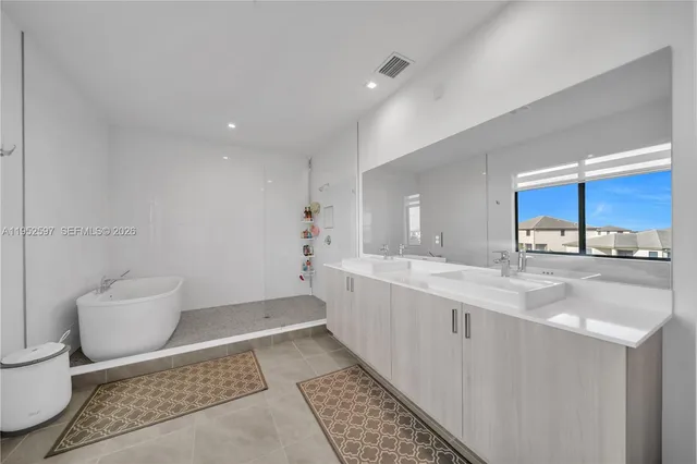 a large white kitchen with a sink stainless steel appliances and cabinets