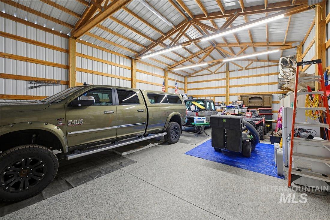 24623 Falcon Lane Caldwell, ID 83607 - Photo 33 of 40 Spacious garage featuring a durable epoxy floor, exposed wood beam vaulted ceiling, ample overhead lighting, and corrugated metal wall panels