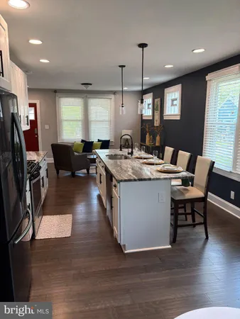 a living room with stainless steel appliances granite countertop furniture wooden floor and a view of kitchen