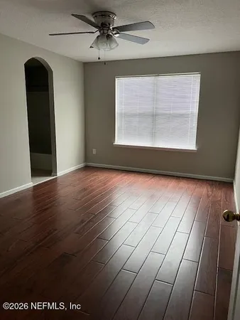 an empty room with wooden floor fan and windows