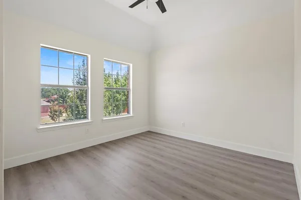 an empty room with wooden floor and windows