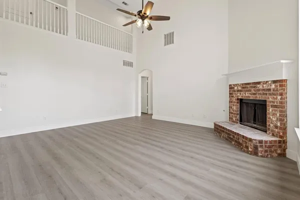 an empty room with wooden floor a fireplace and windows
