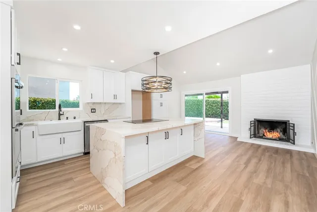 a large kitchen with stainless steel appliances granite countertop a large center island a stove a refrigerator cabinets and a wooden floor