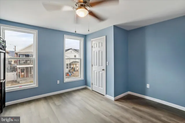 a view of an empty room with window and wooden floor