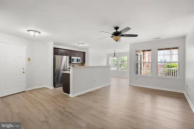 a view of an empty room with a kitchen and wooden floor