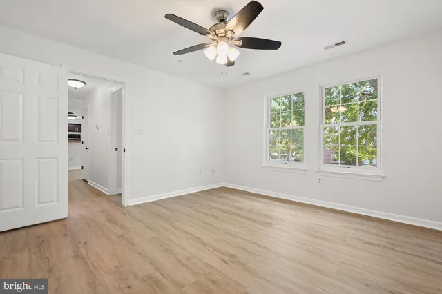an empty room with wooden floor and windows