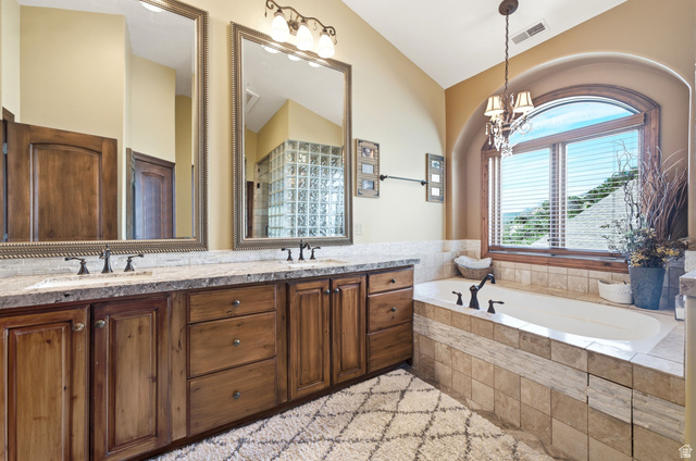 335 Bern Way Midway, UT 84049 - Photo 35 of 88 Soaking tub with tiled surround, arched window, and chandelier