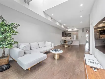 a living room with kitchen island a dining table chairs and wooden floor