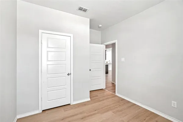 an empty room with wooden floor & closet area