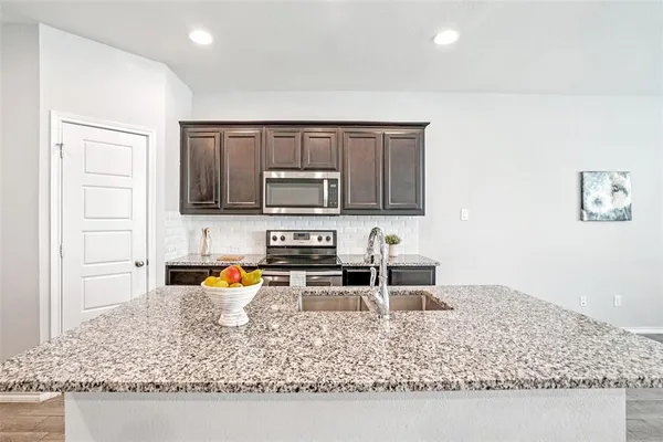 a kitchen with stainless steel appliances granite countertop a sink stove and refrigerator