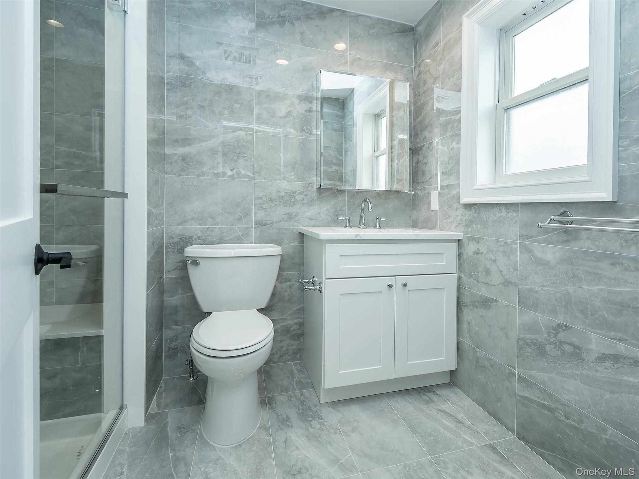 35 B Dunwood Road Port Washington, NY 11050 - Photo 18 of 35 a bathroom with a granite countertop toilet a mirror and a shower