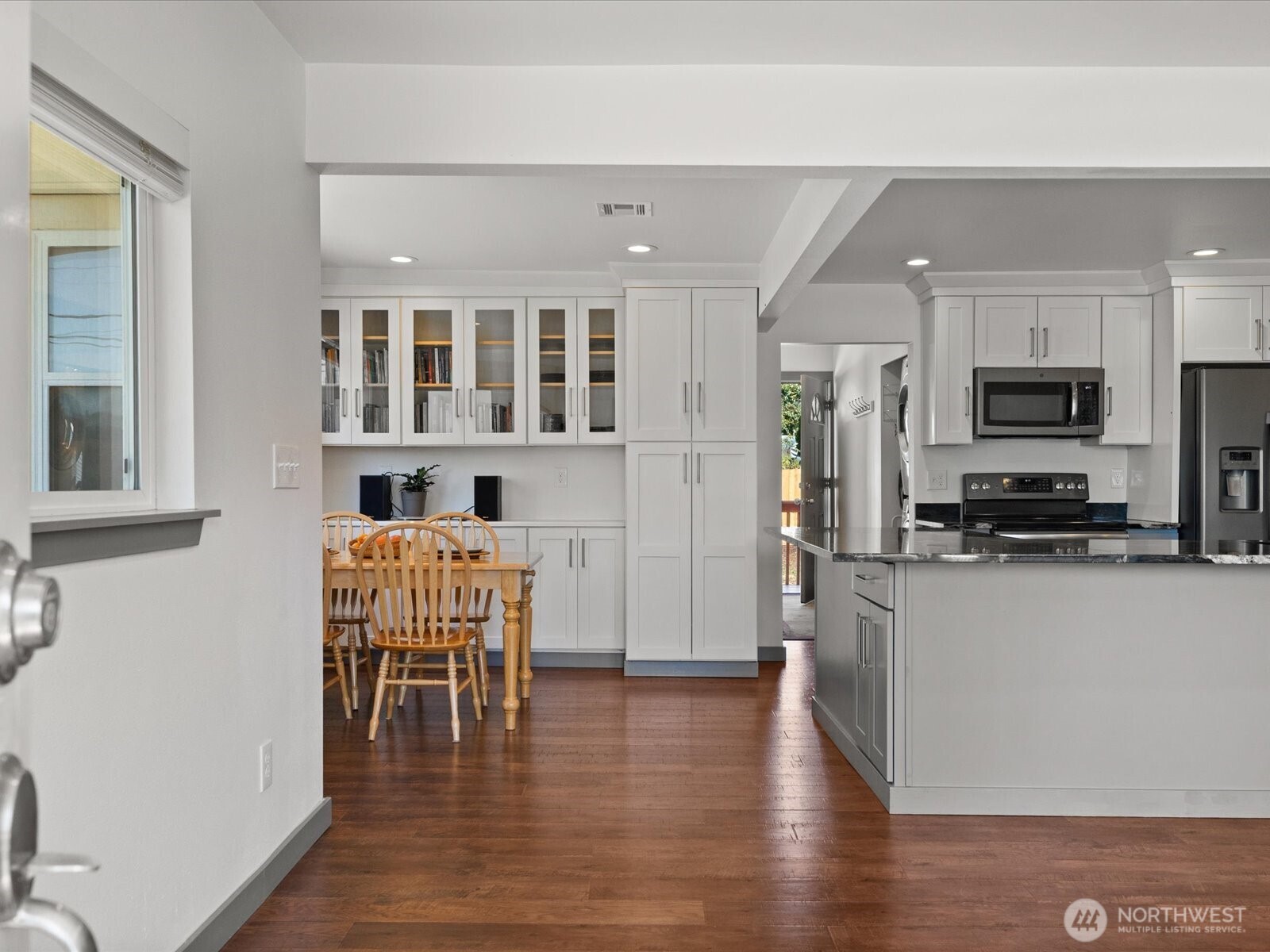 10126 Northeast 186th Street Bothell, WA 98011 - Photo 20 of 40 a kitchen with stainless steel appliances granite countertop a stove top oven a sink a dining table and chairs with wooden floor