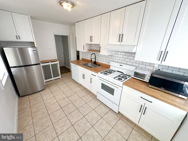 a kitchen with white cabinets a sink a stove a refrigerator and a window