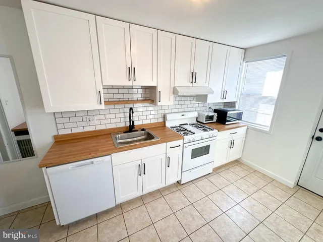 a kitchen with white cabinets a sink a stove and a window