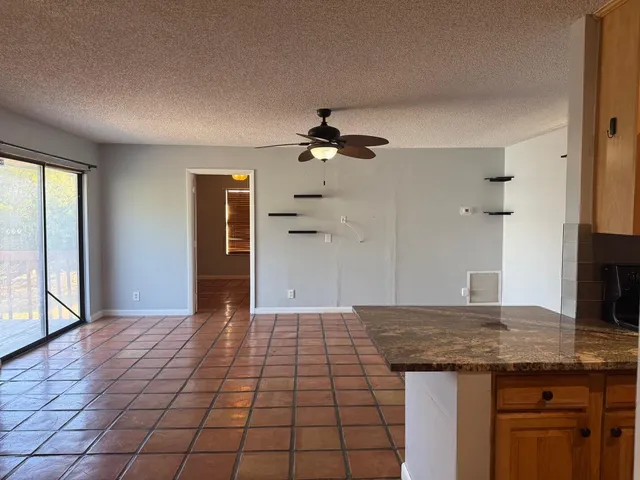 a view of a kitchen with granite countertop a sink and a refrigerator