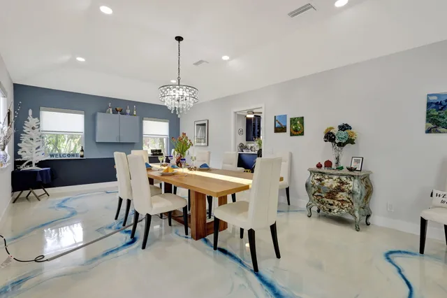 a view of kitchen island with stainless steel appliances wooden floor dining table and chairs