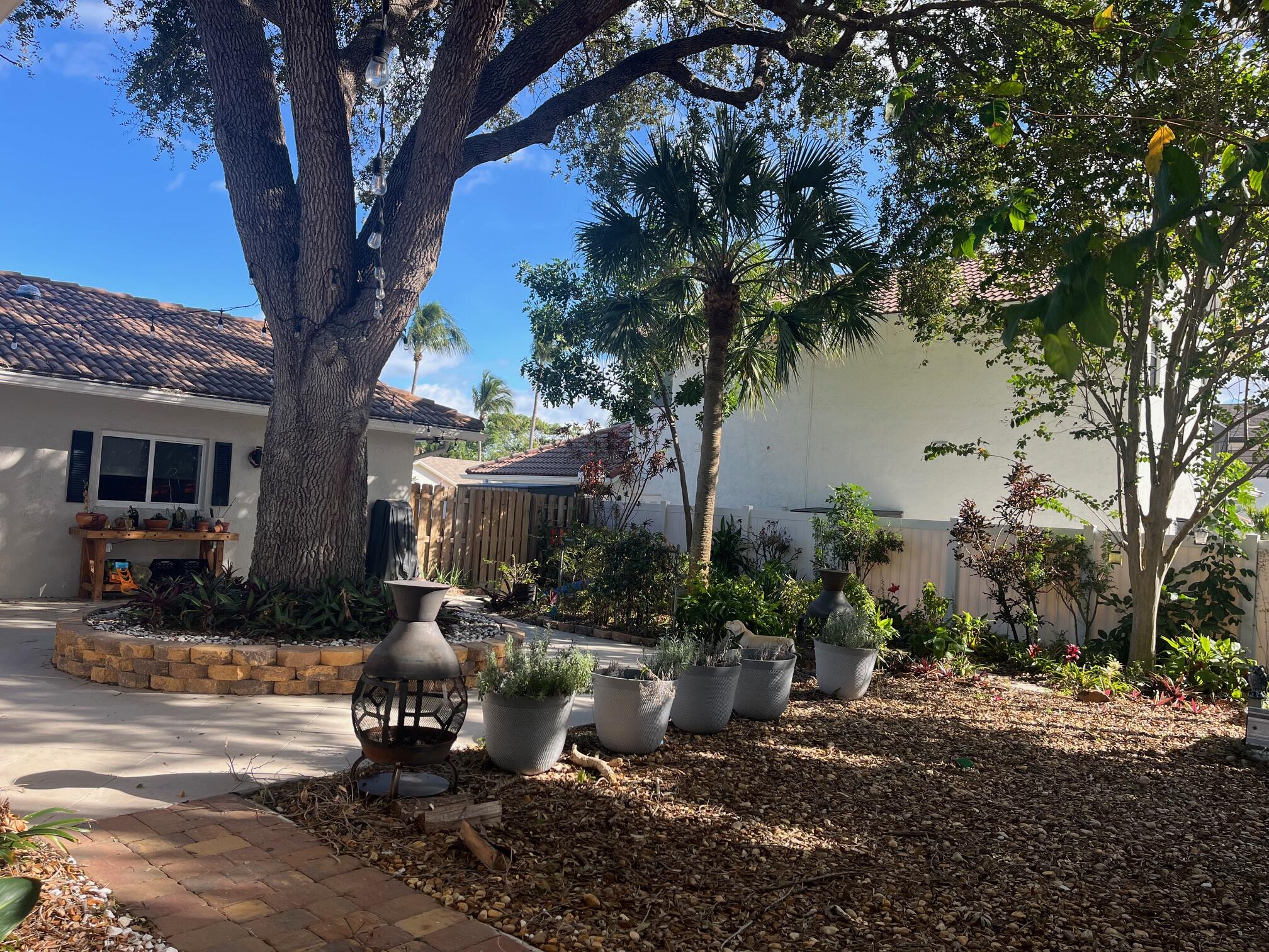 7598 West Country Club Boulevard Boca Raton, FL 33487 - Photo 21 of 103 a front view of a house with garden and trees