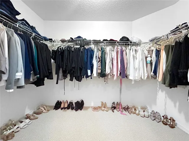 a view of walk in closet with clothes and shoes