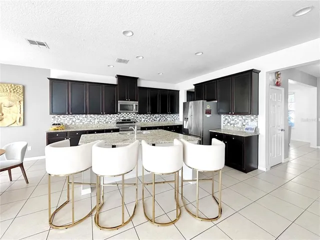 a kitchen with stainless steel appliances kitchen island granite countertop a refrigerator and a stove top oven