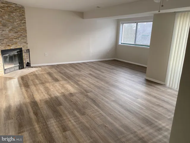 an empty room with wooden floor fireplace and windows