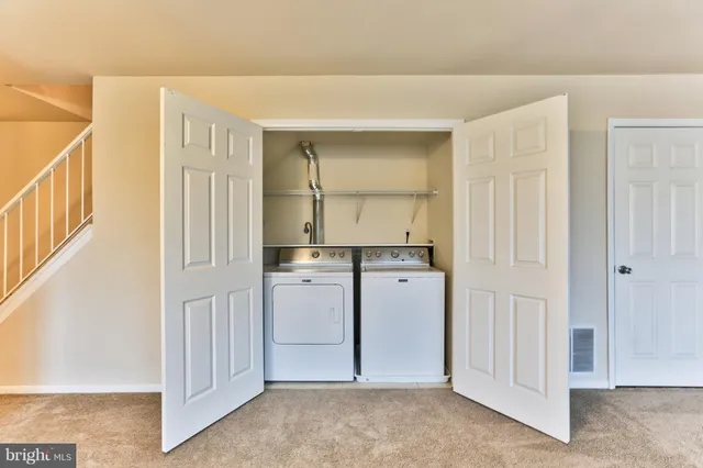 a view of kitchen with refrigerator and white cabinets