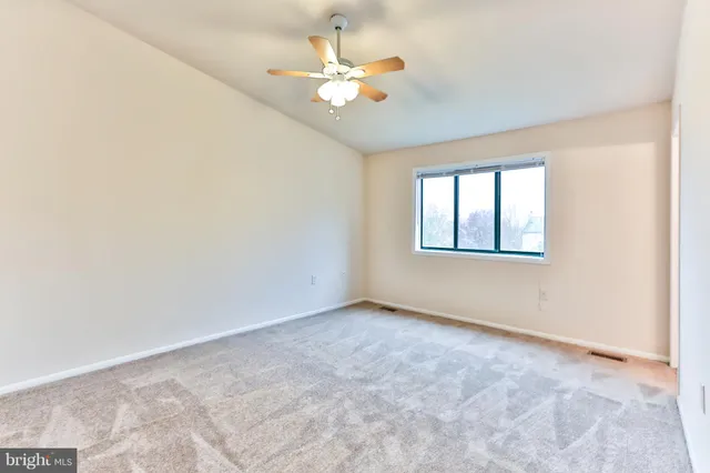 an empty room with closet and ceiling fan