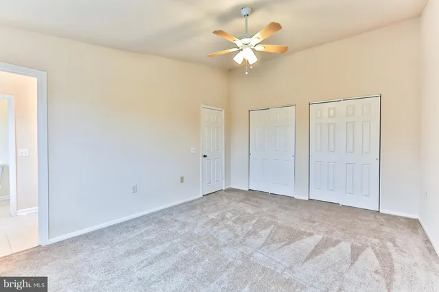 a view of an empty room with a chandelier fan