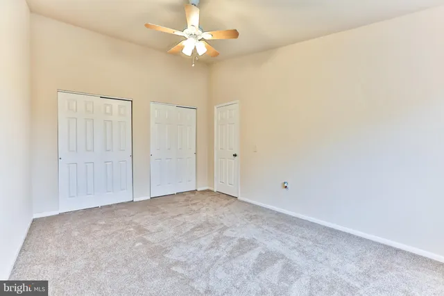 an empty room with a chandelier fan and windows