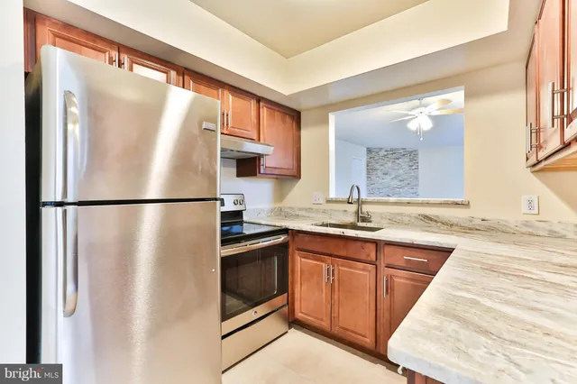 a kitchen with stainless steel appliances granite countertop a refrigerator a sink and a stove with wooden floor