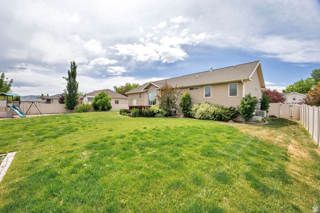 2912 South 1080th Street West Logan, UT 84321 - Photo 42 of 43 Expansive backyard with a manicured lawn, full fencing, mature landscaping, and a multi-level wood deck