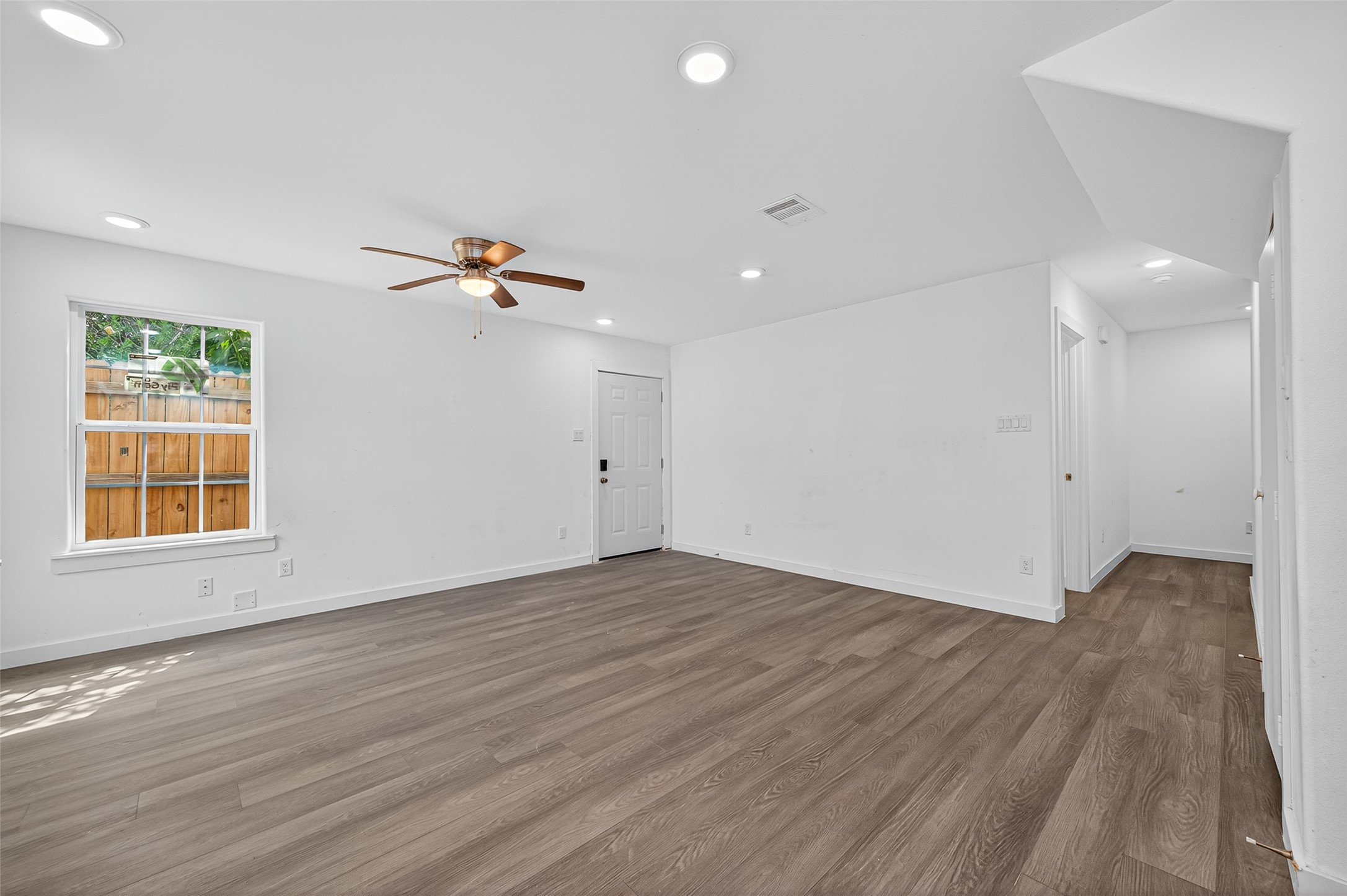 9405 Madera Road Houston, TX 77078 - Photo 11 of 32 an empty room with wooden floor a ceiling fan and windows