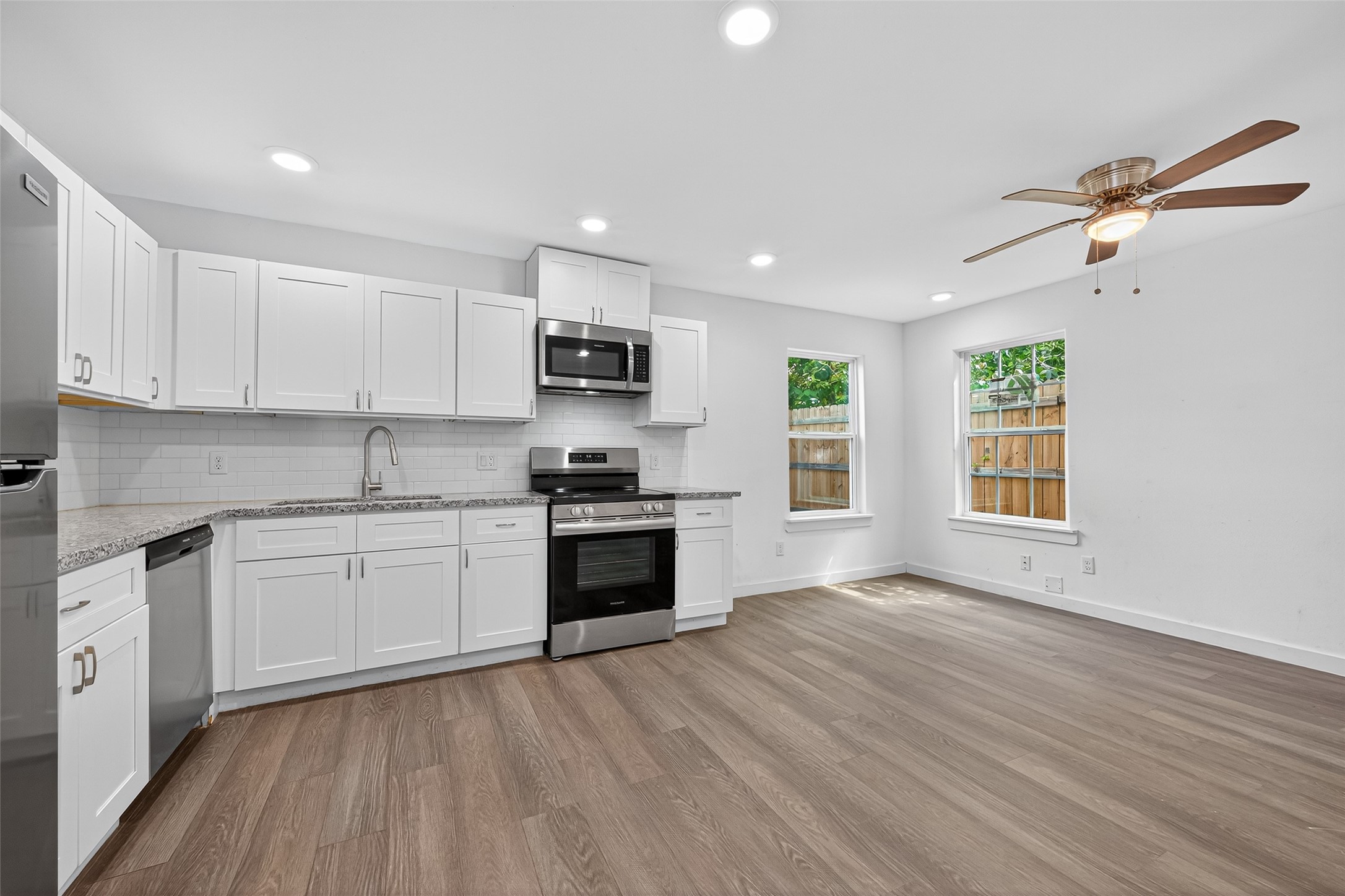 9405 Madera Road Houston, TX 77078 - Photo 9 of 32 a kitchen with granite countertop a stove top oven a sink dishwasher and a refrigerator with wooden floor